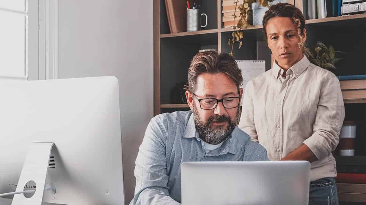 Image of person engaged on a laptop while another person observes