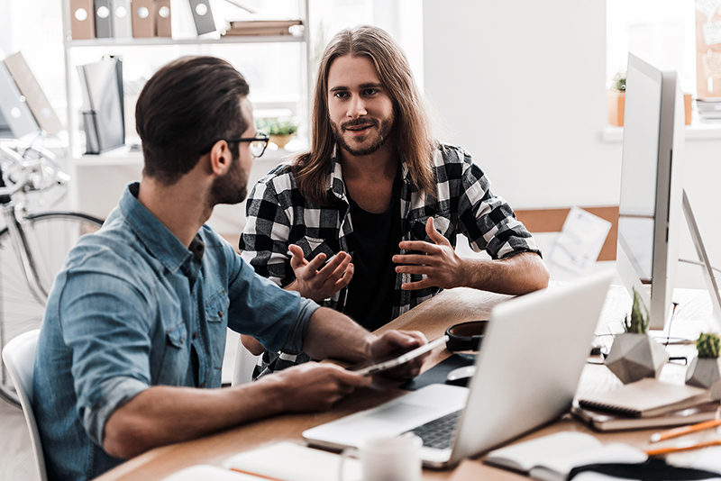Two men talking in front of a computer