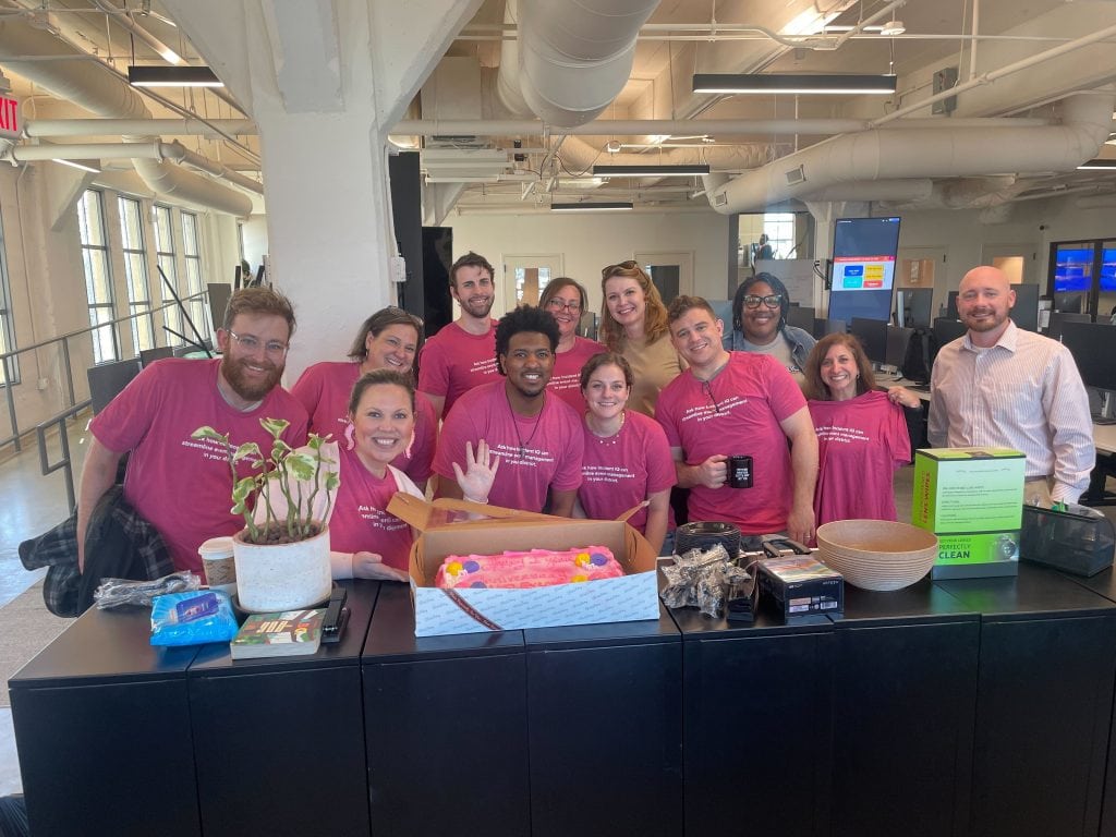 A group of smiling Incident IQ employees posing with a birthday cake.