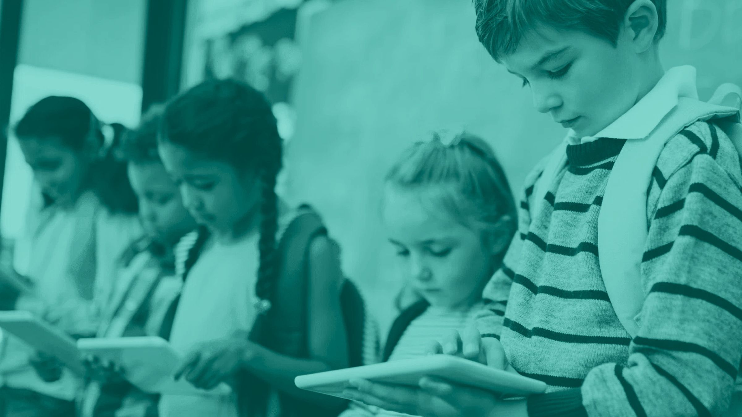 row of students in a classroom each holding a school tablet