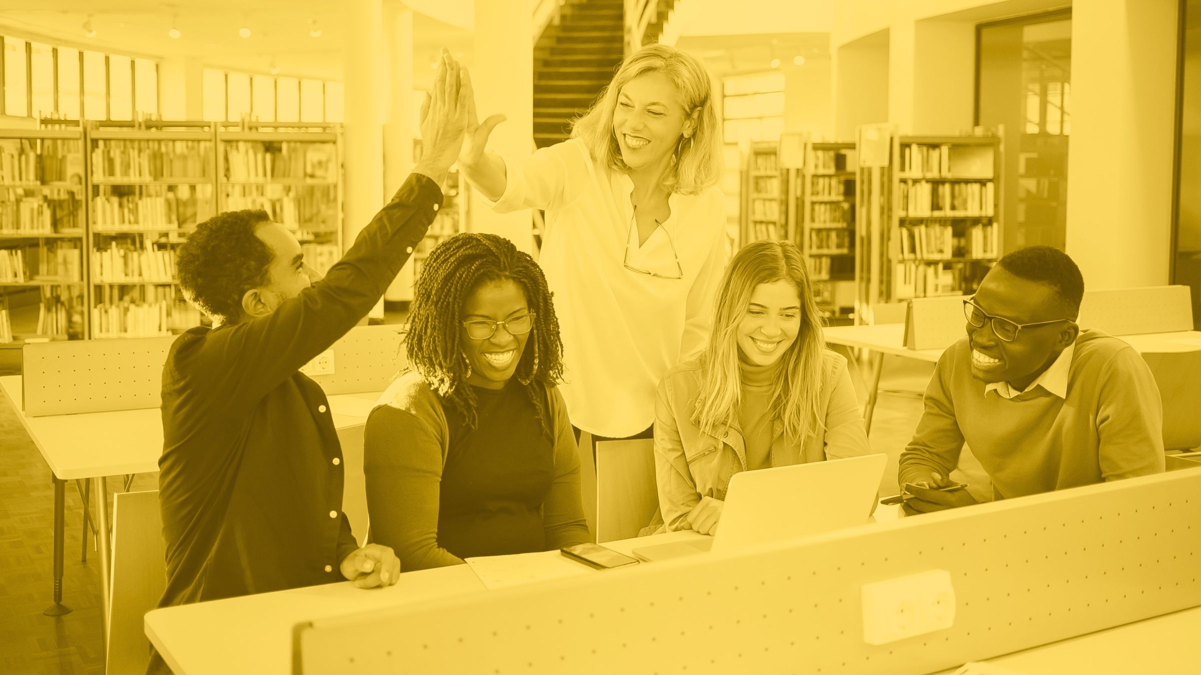group of school staff sitting around a computer happy