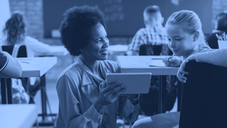image of a teacher holding up a tablet to a student to review work. three icons float next to the image, a heart, speed gauge, and a it user.